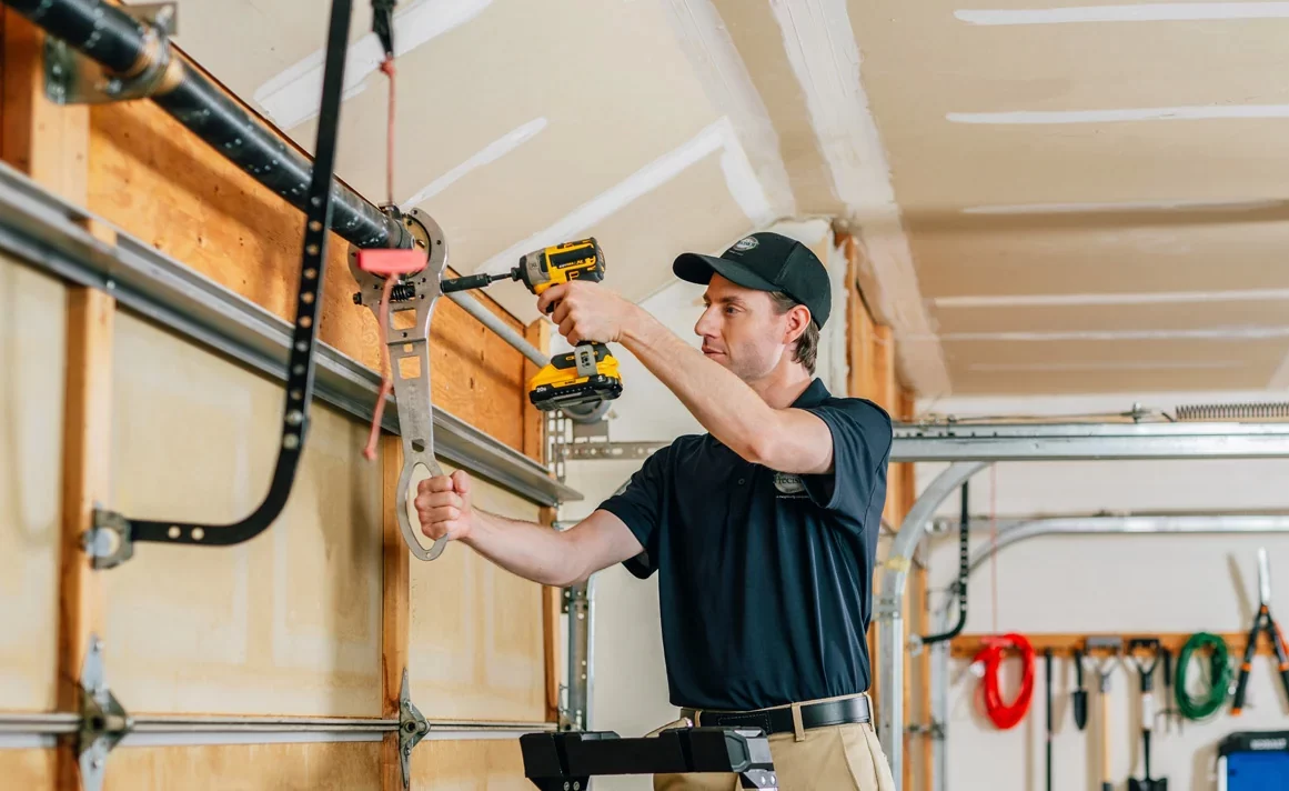 Professional technician performing seasonal maintenance on a modern garage door in a suburban home.